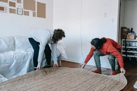 A couple packing a carpet to protect it when moving